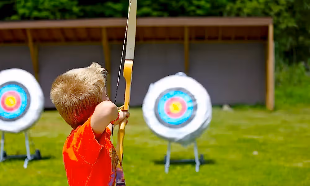 Boy shooting an arrow at a target. 