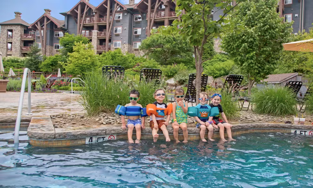 Children with floaties on sitting on edge of outdoor Biosphere pool.