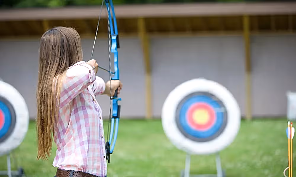 Woman doing target practice with bow and arrow.