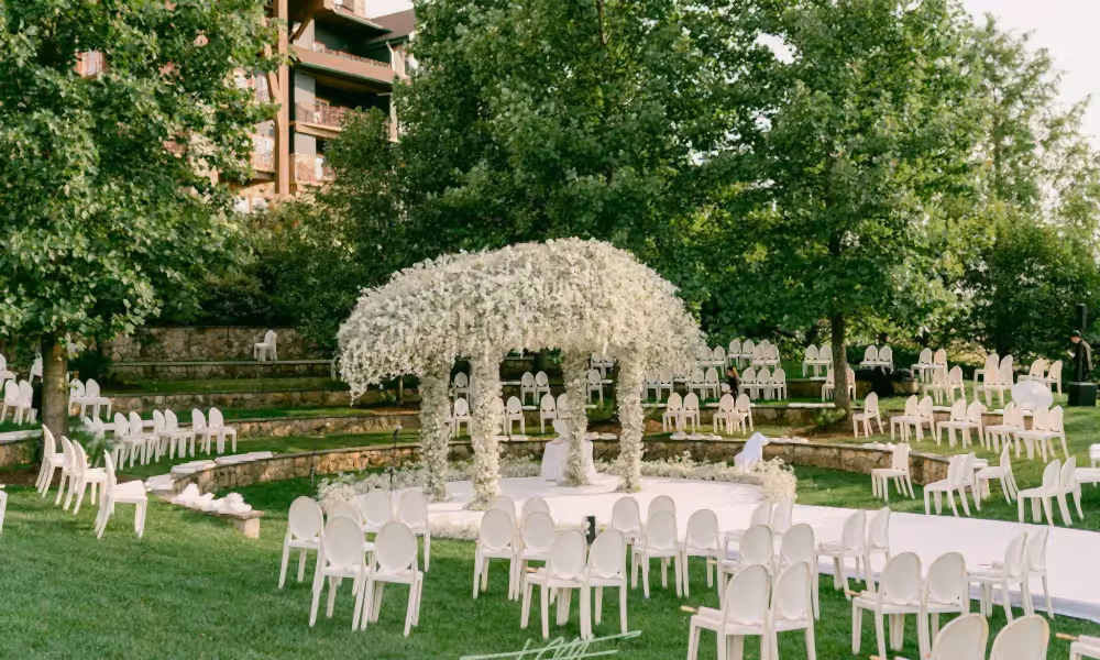 Wedding ceremony in amphitheater with white chairs and white flowers.