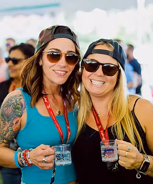 Two women holding mini beer samplers.