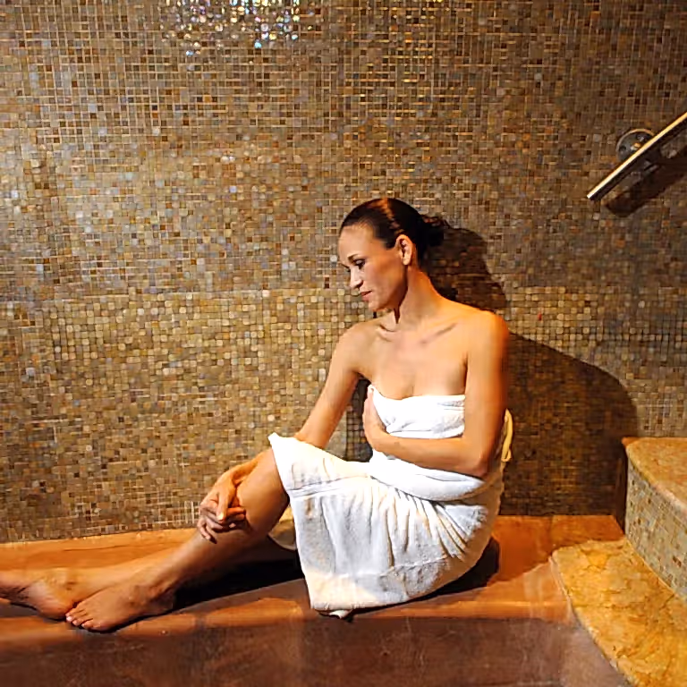 Woman in white towel relaxing in Elements Spa sauna.